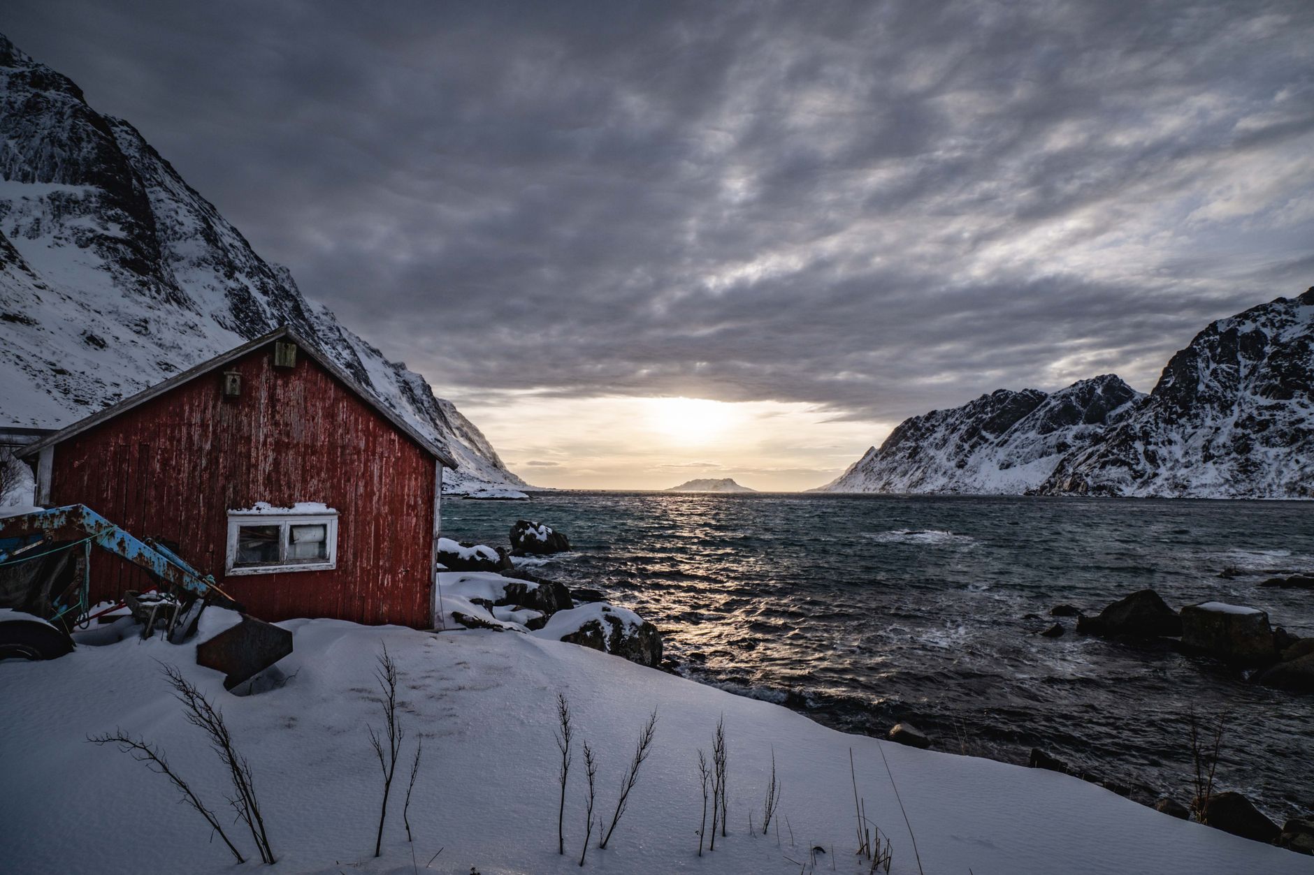 Solitary red timber cabin at the base of dramatic Norwegian mountains